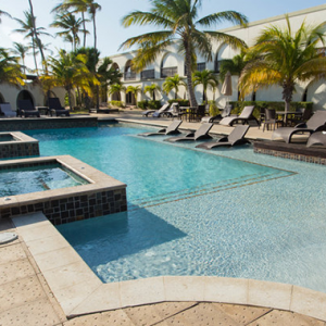 Large pool surrounded by palm trees located at the Talk of the Town Hotel & Beach Club in Oranjestad, Aruba.